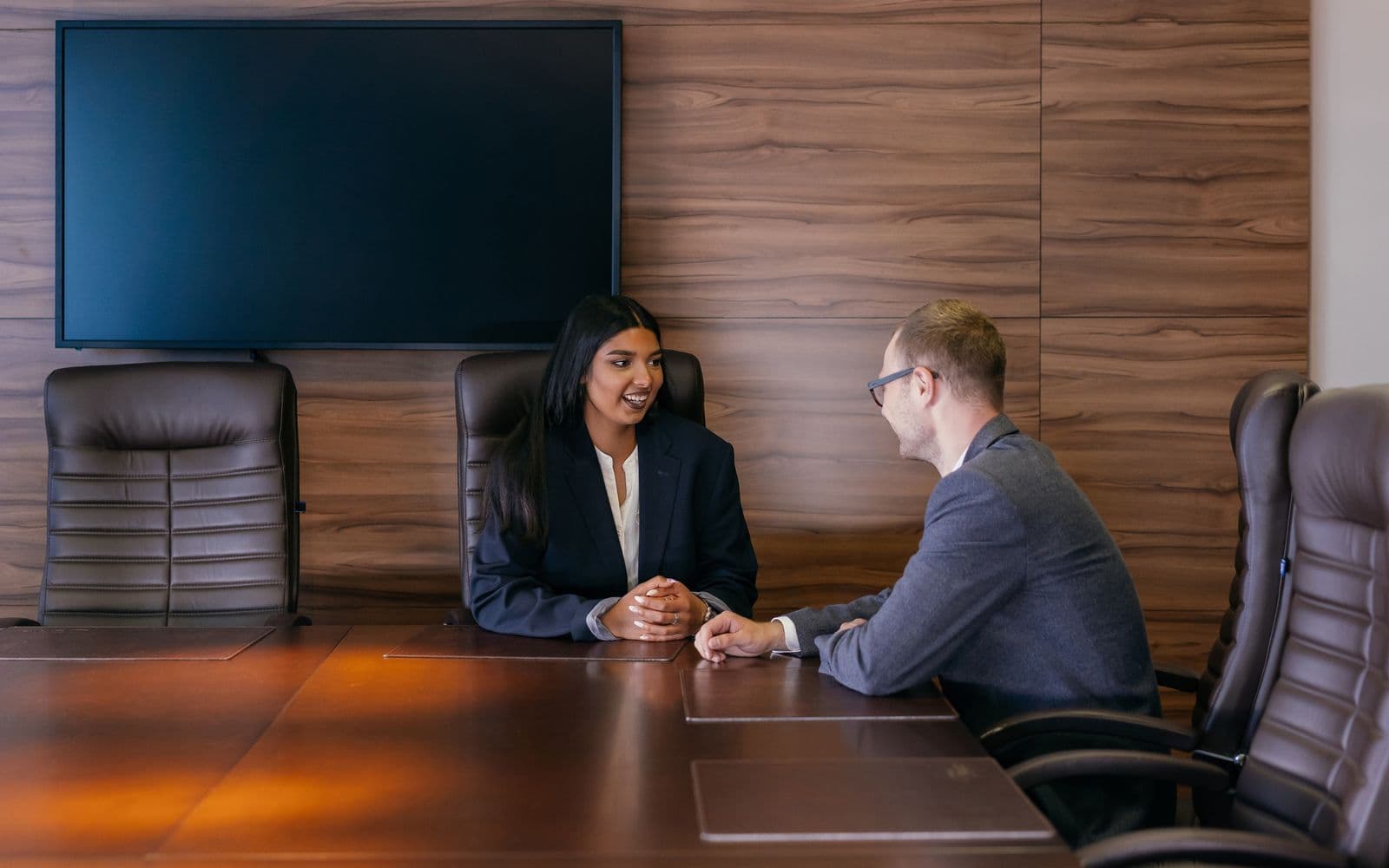 Two people in a boardroom meeting across a table