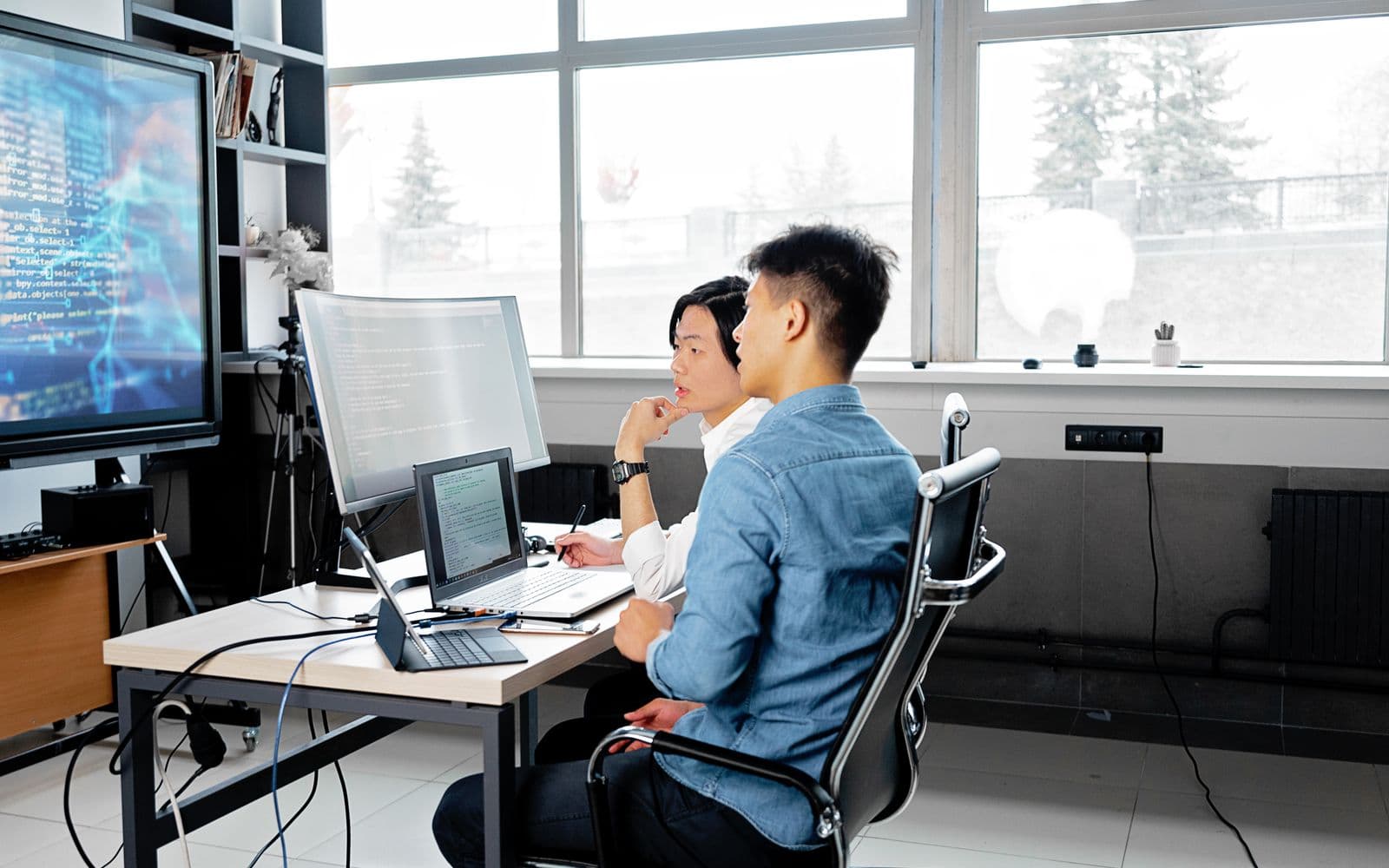 Developers working at desks with code on their screens